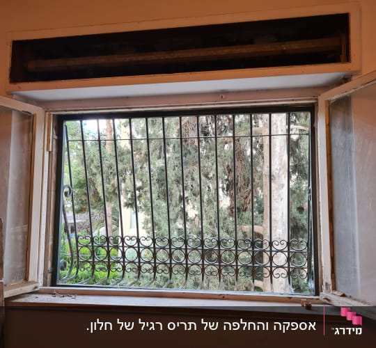 חלון פתוח עם תריסים חסרים ומסגרת עץ